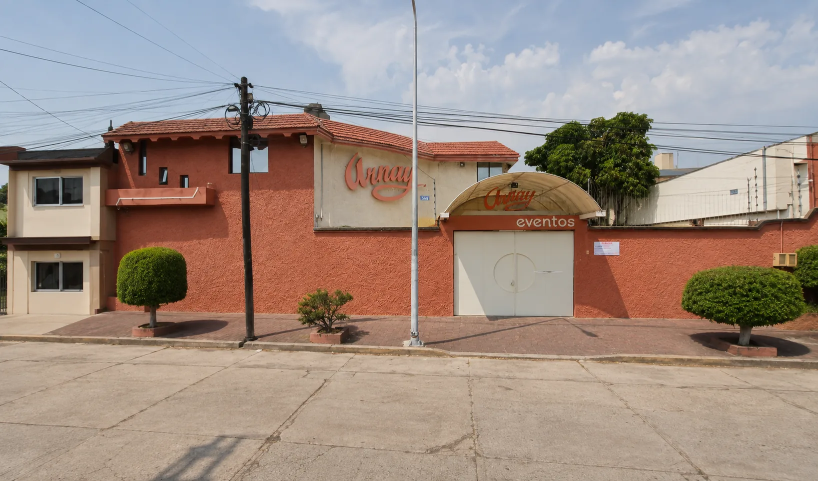 Vista amplia de la fachada del Salón Arnay desde la calle con jardineras y acceso completo