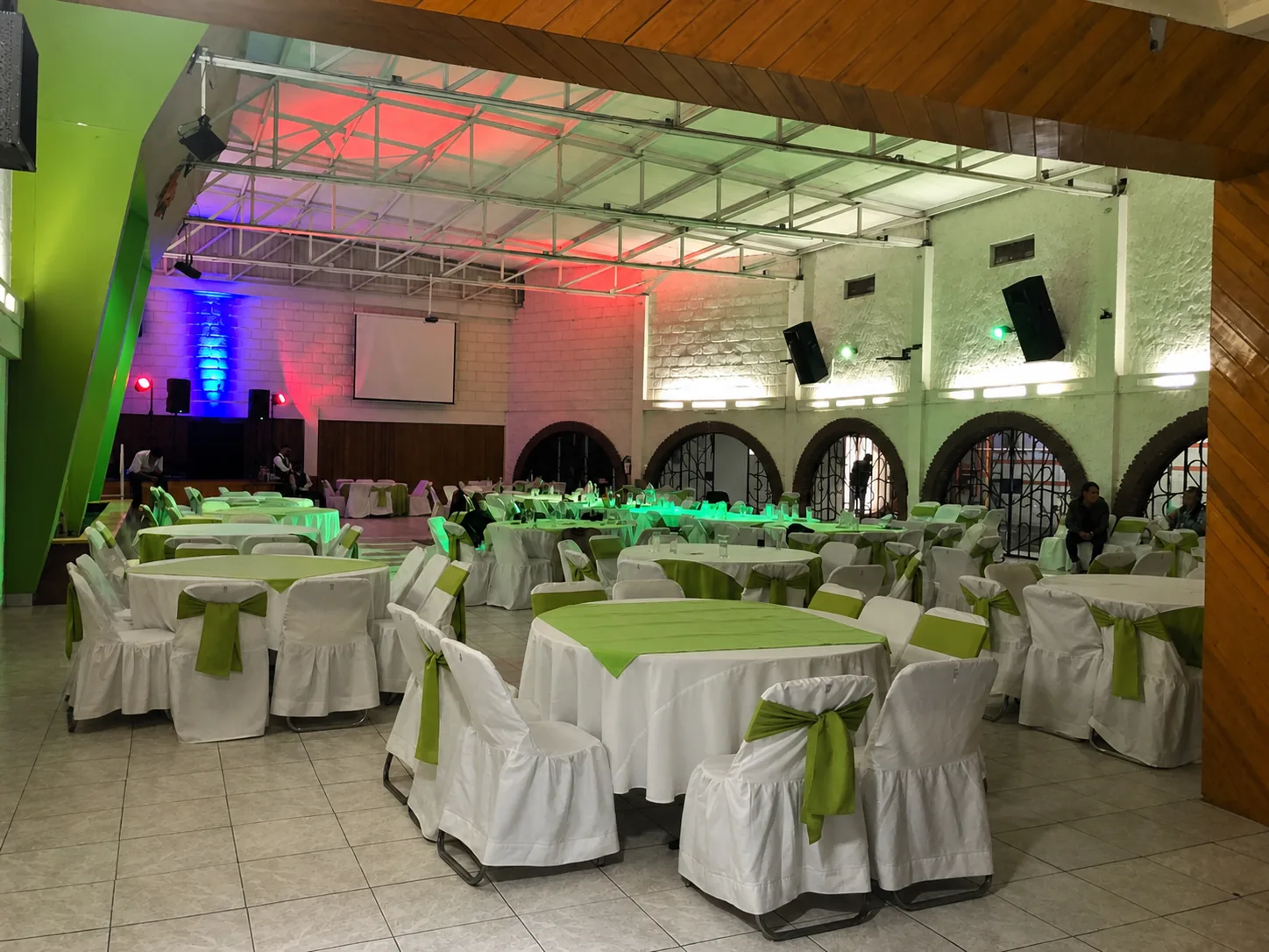 Celebración en el interior del salón con iluminación verde, roja y morada