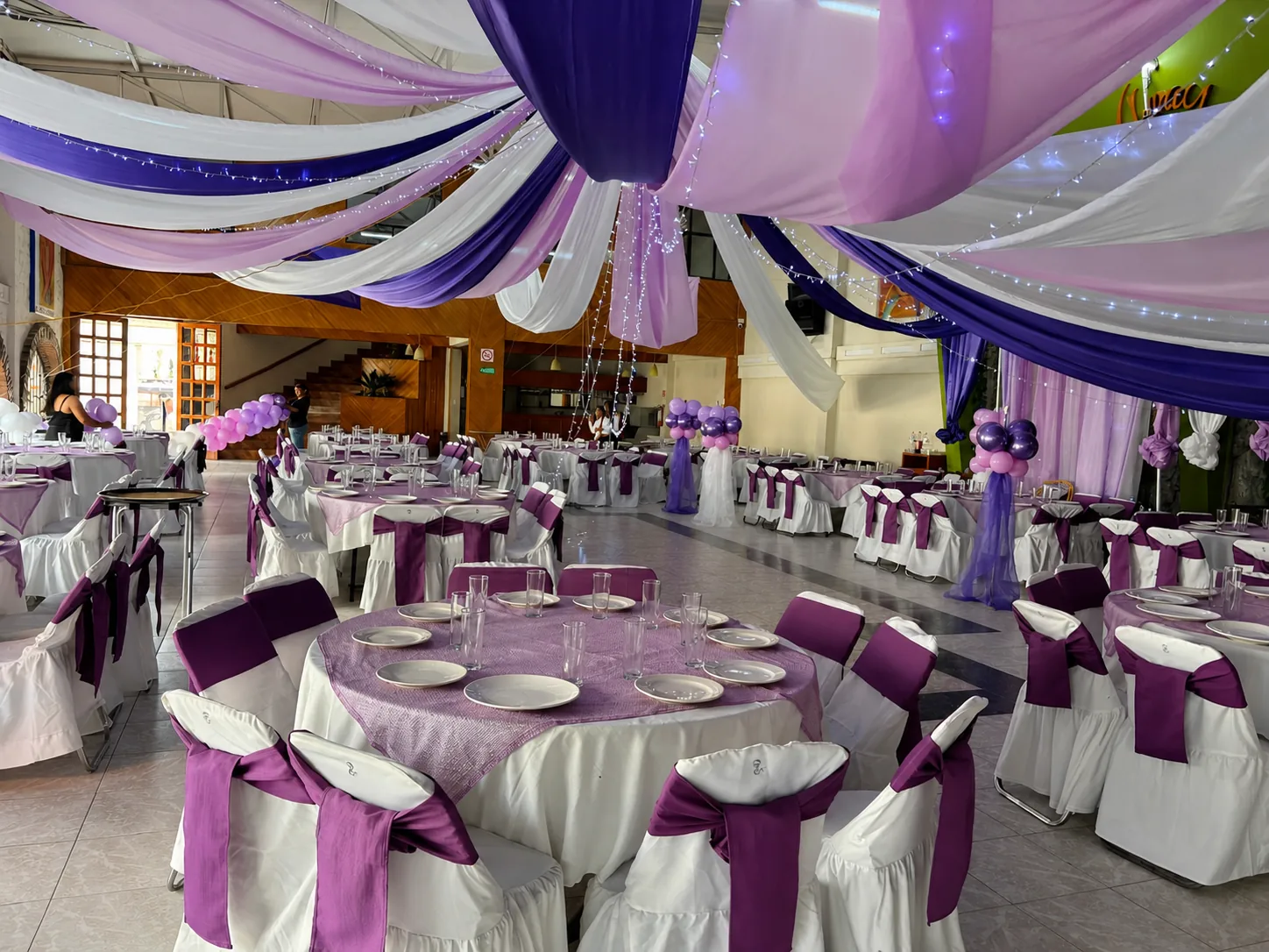 Interior del salón con cortinas lavanda y mesas decoradas